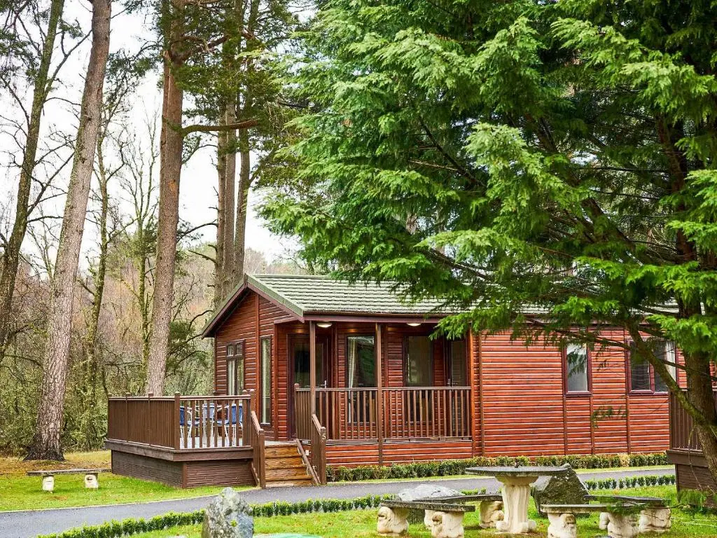 a small cabin in the woods with a deck at Lodge E- Uk33091 in Dinnet