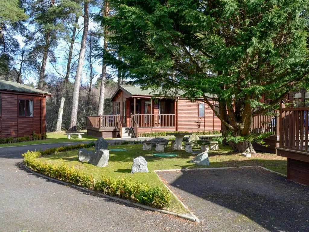 a cabin with rocks in front of a house at Lodge E- Uk33091 in Dinnet