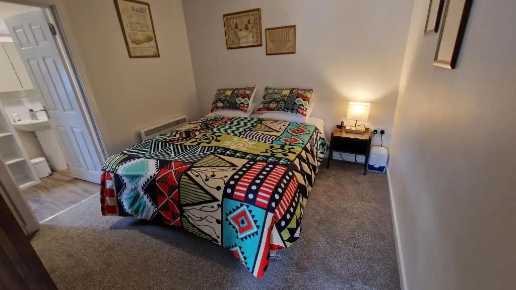 a bedroom with a bed with a colorful comforter at Meadows 2 in Auldearn