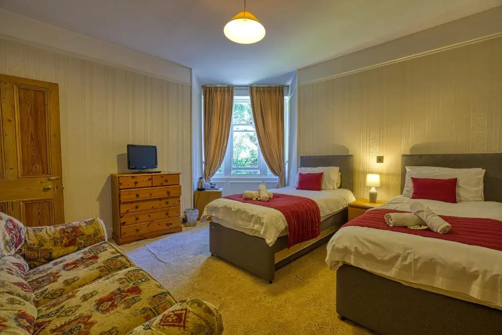 a hotel room with two beds and a couch at Woodlands Bed and Breakfast in Dornoch