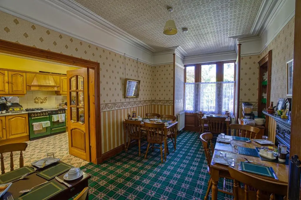 a kitchen and dining room with tables and chairs at Woodlands Bed and Breakfast in Dornoch