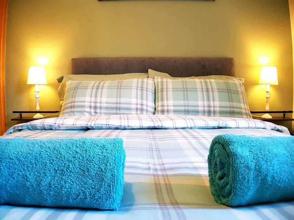 a bed with two pillows and blue towels on it at Hill View 2 bedroom free parking in Inverness