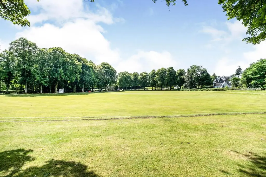 a large green field with trees in the background at The Ness Apartment Highland Club Scotland in Fort Augustus
