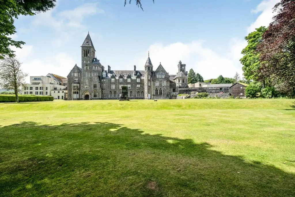 an old castle with a grass field in front of it at The Ness Apartment Highland Club Scotland in Fort Augustus