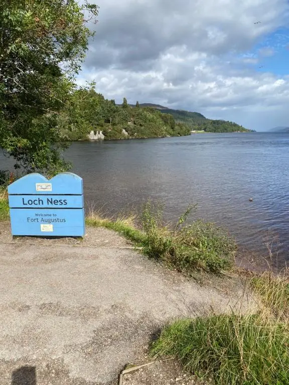 a sign sitting on the side of a body of water at Hayfield lodge in Spean Bridge