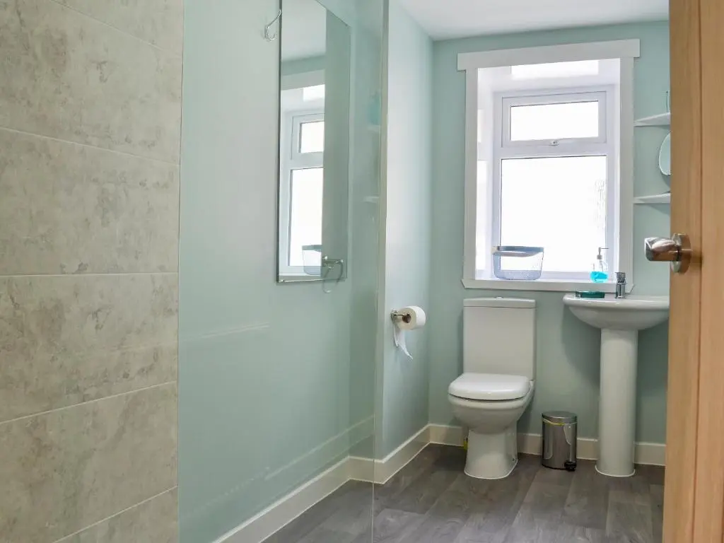 a bathroom with a toilet and a sink and a window at Three Creeks Cottage in Portknockie