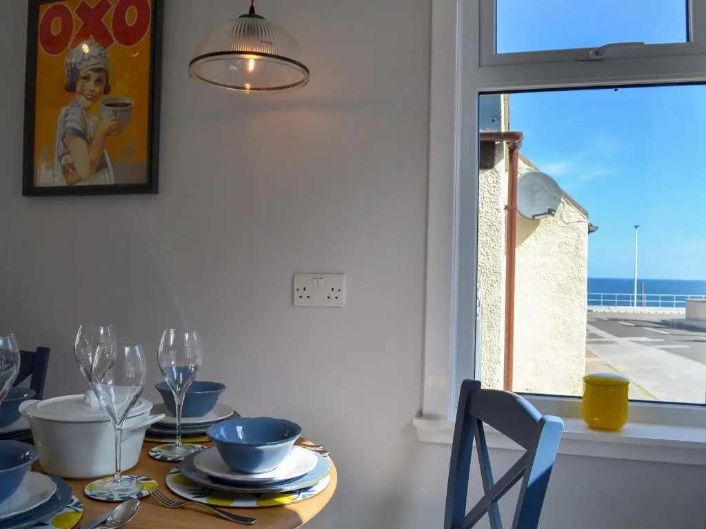 a dining room with a table with a view of the ocean at Three Creeks Cottage in Portknockie