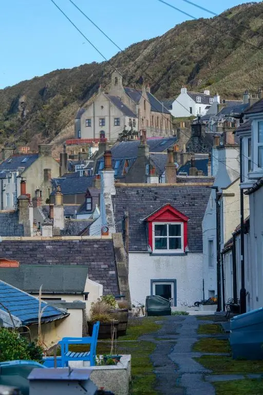 a group of houses with a hill in the background at Finest Retreats - Ellie-Jo Cottage in Gardenstown