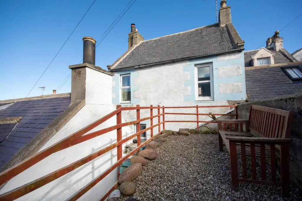 a house with a fence and a bench in front of it at Finest Retreats - Ellie-Jo Cottage in Gardenstown