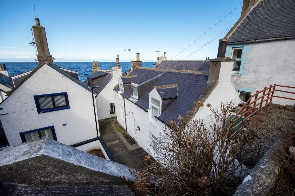 a group of houses with the ocean in the background at Finest Retreats - Ellie-Jo Cottage in Gardenstown