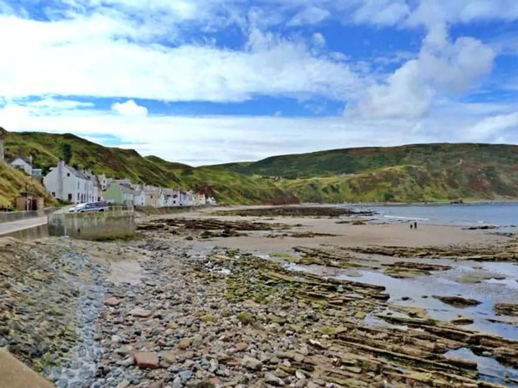 a beach with rocks and houses on the shore at Finest Retreats - Ellie-Jo Cottage in Gardenstown