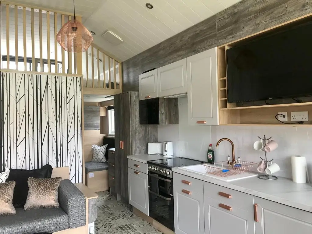 a kitchen with white cabinets and a couch in a room at 2 Bed Inverness - Sleeps 4 - Parking - Wifi in Inverness