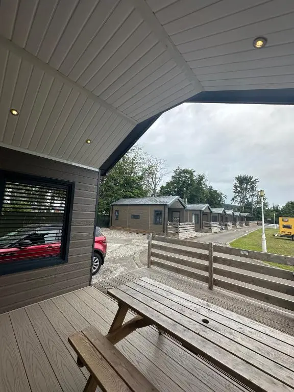 a wooden bench sitting on the porch of a building at Self-Catering Lodge with Hot Tub in Inverness