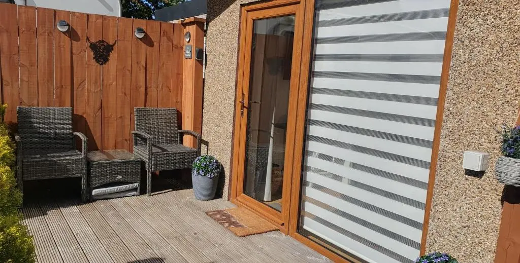 a patio with two chairs and a wooden door at The Nook in Inverness