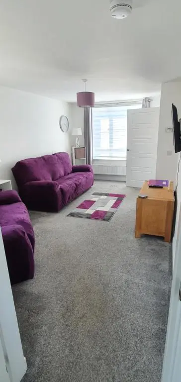a living room with a purple couch and a table at Kellys in Inverness