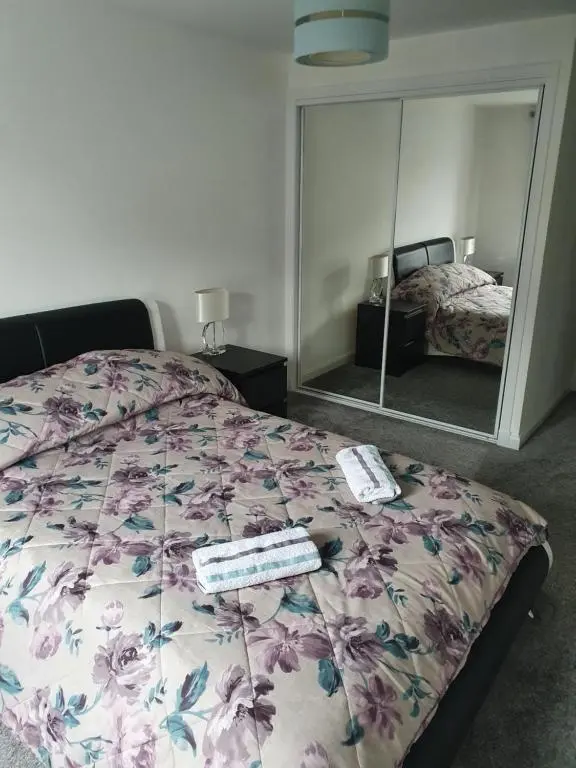 a bedroom with a bed with a floral bedspread and a mirror at Kellys in Inverness