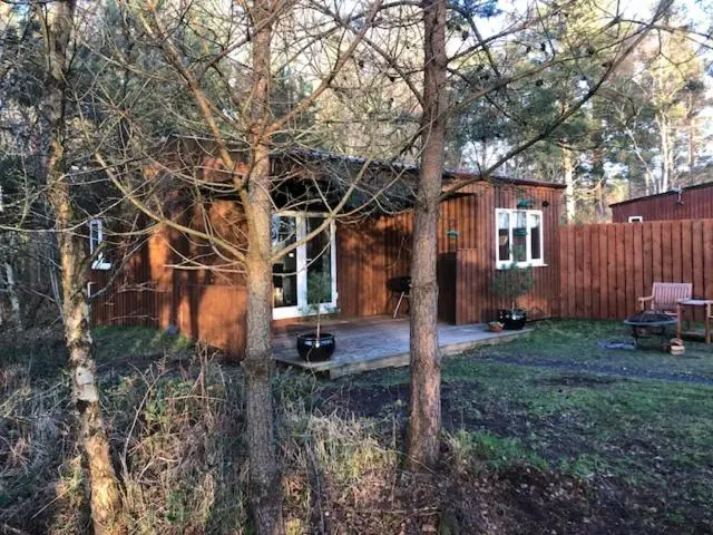 a log cabin with a porch and a fence at The Cabin at Easter Arr in Auldearn