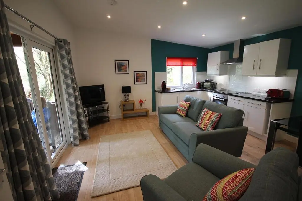 a living room with a couch and a kitchen at The Cabin at Easter Arr in Auldearn