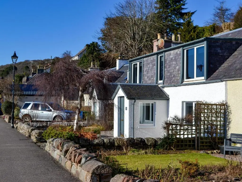 a white house with a car parked in front of it at The Shore in Fortrose