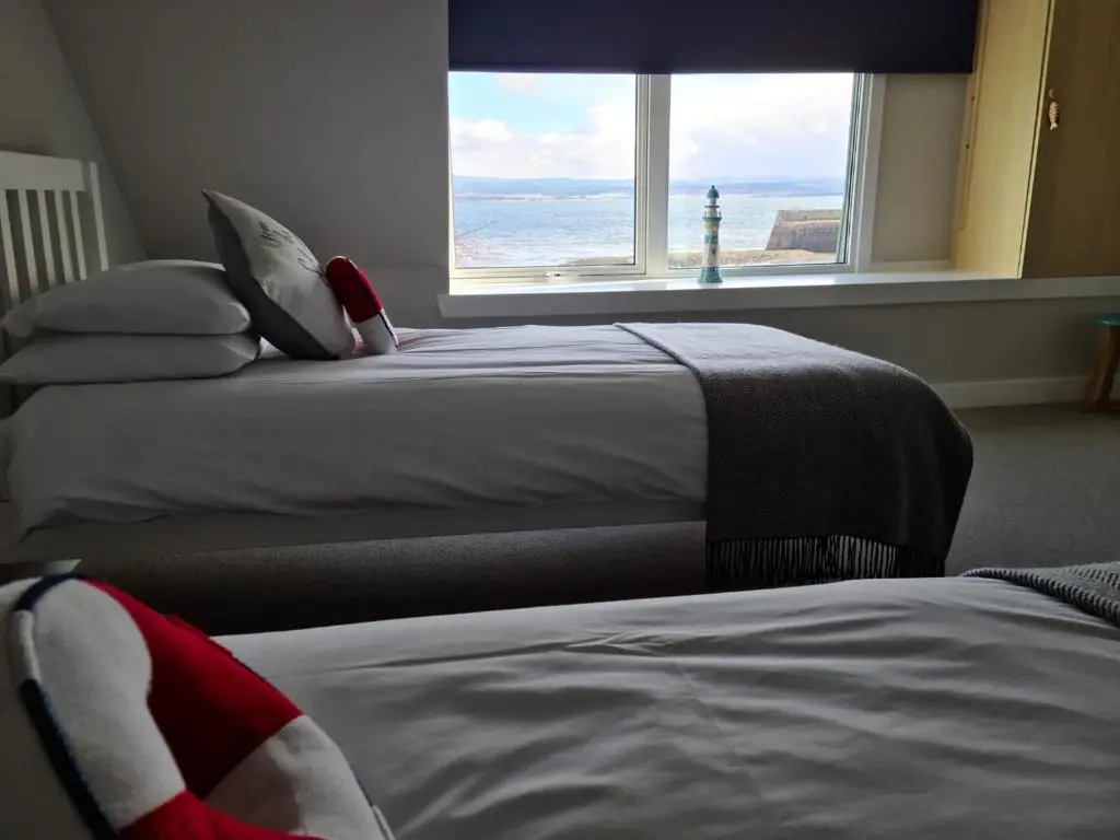 two beds in a room with a view of the ocean at The Shore in Fortrose