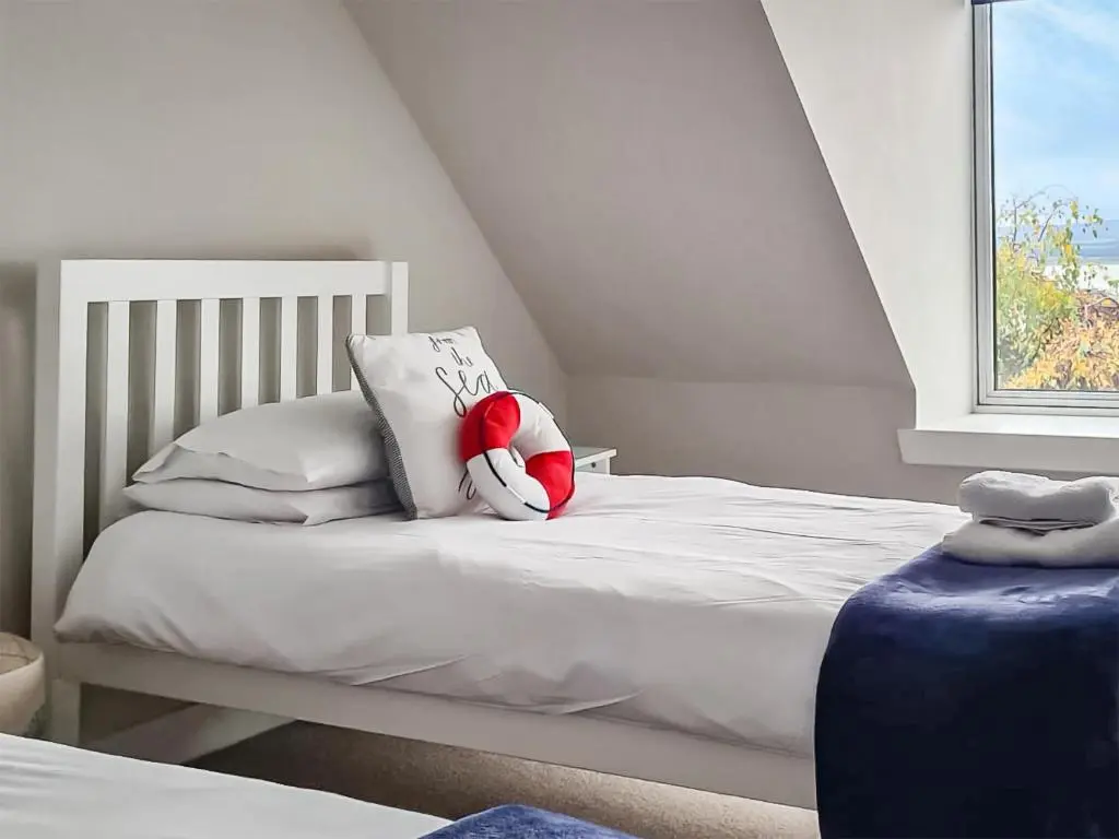 a white bed with a red stuffed animal on it at The Shore in Fortrose