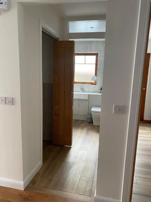 a bathroom with a toilet and a sink and a door at The Nook Holiday Cottage in Aviemore