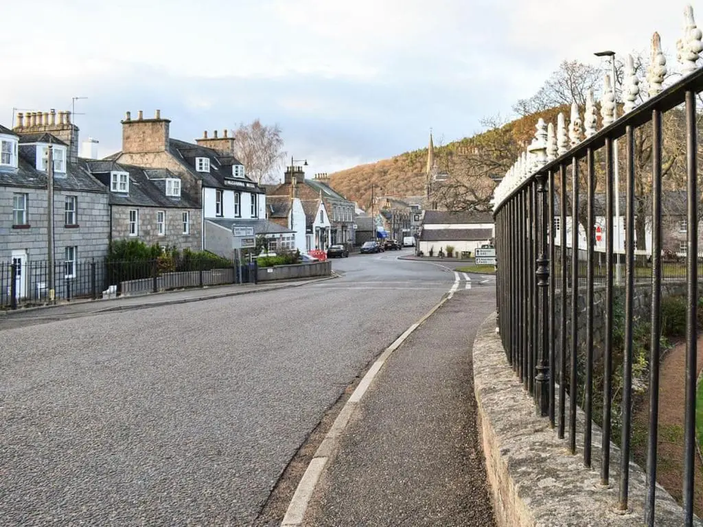 an empty street with a fence and houses at Lovely 2 bedroom apt in Ballater on the River Dee in Ballater
