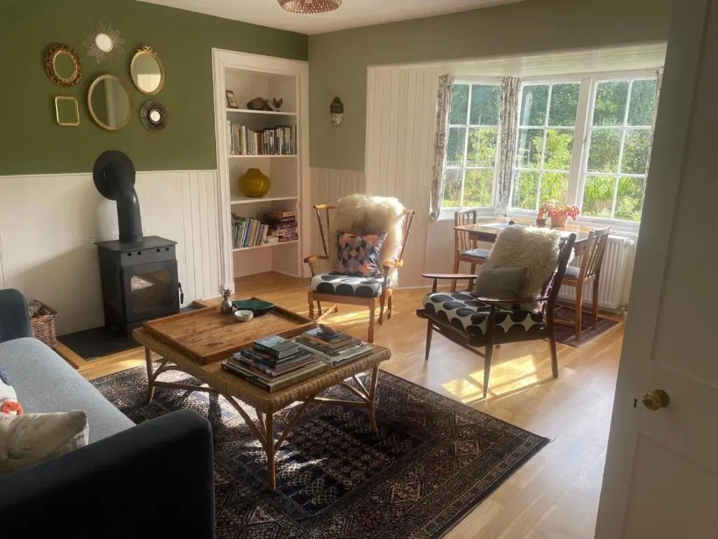 a living room with a fireplace and a table and chairs at Rowan Cottage, CrannachCottages in Garve