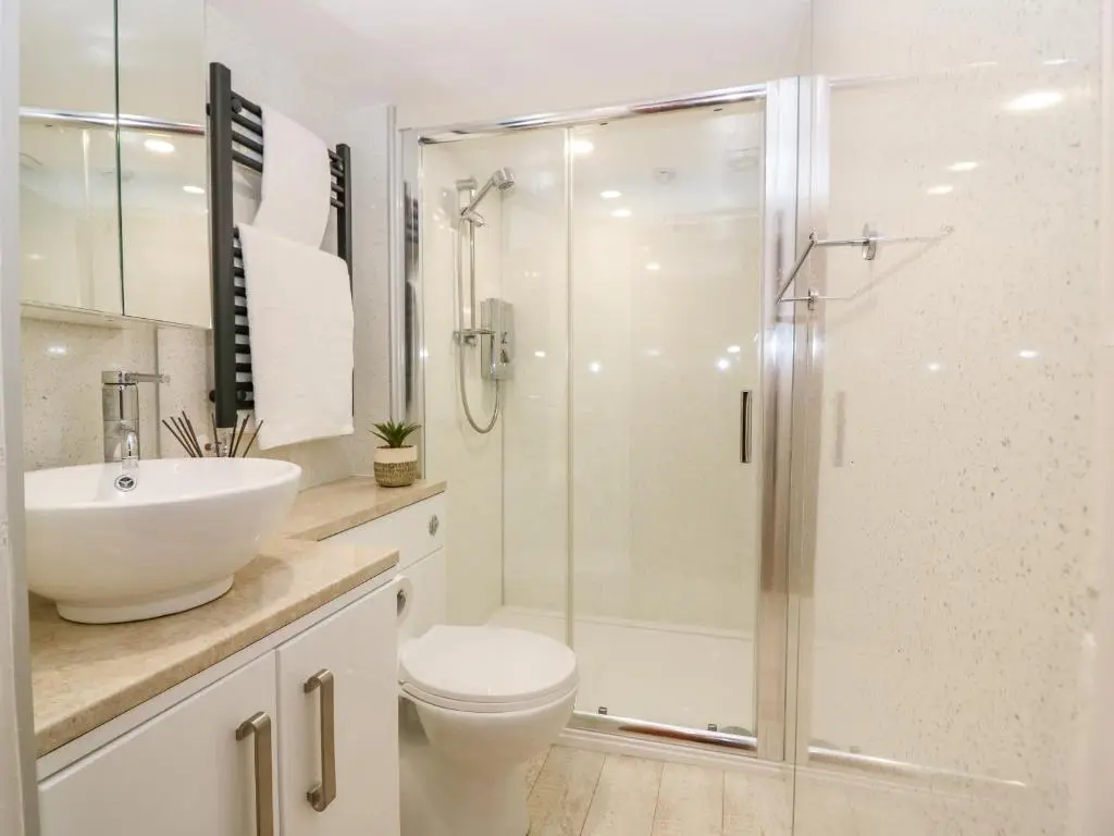 a bathroom with a shower and a toilet and a sink at Gairnlea Cottage in Ballater