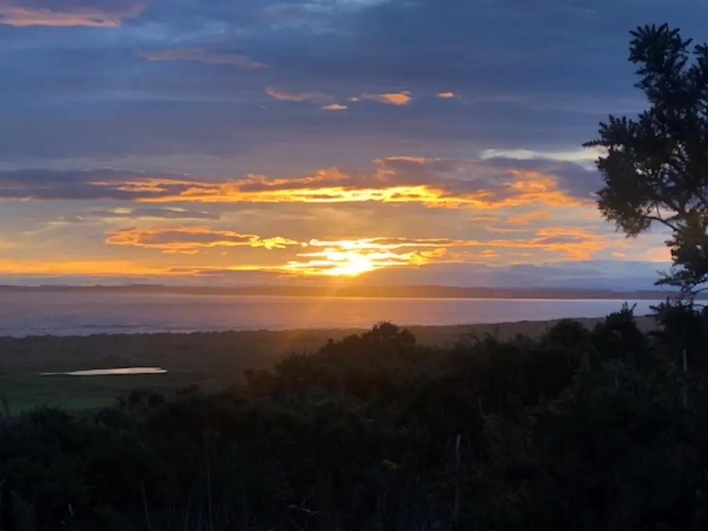 a sunset over the water with the sun setting at Balloan Cottage in Dornoch