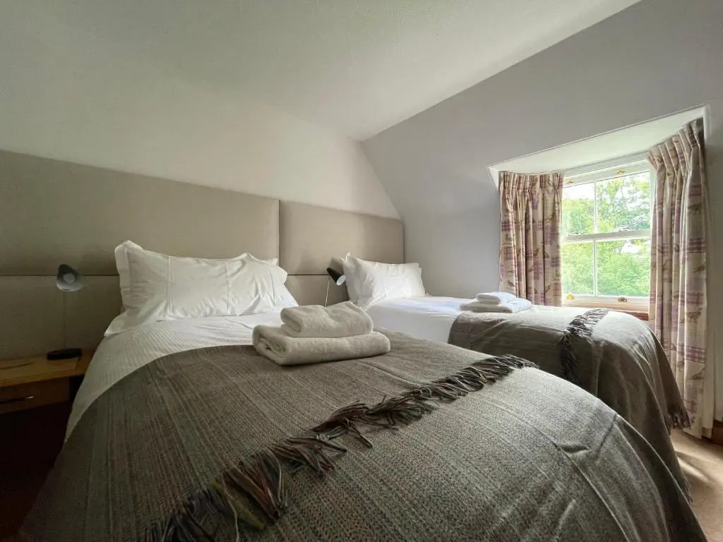 a bedroom with two beds with towels on them at Balloan Cottage in Dornoch