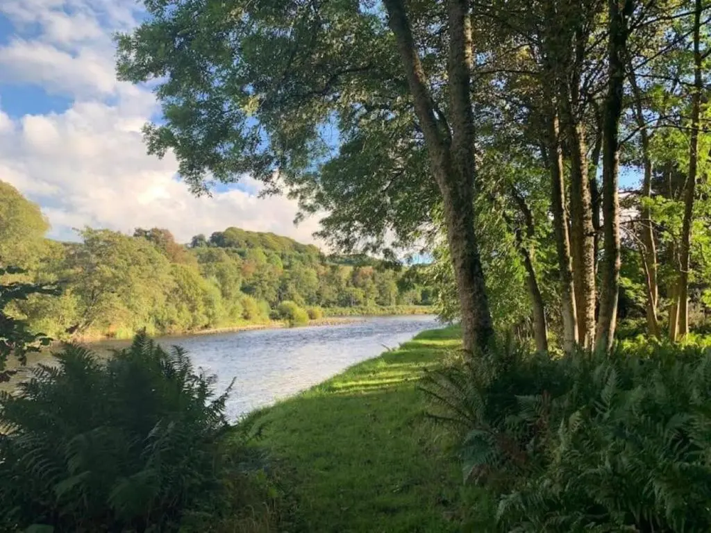 a view of a river with trees and a grass field at Lower Bruntlands in Fochabers