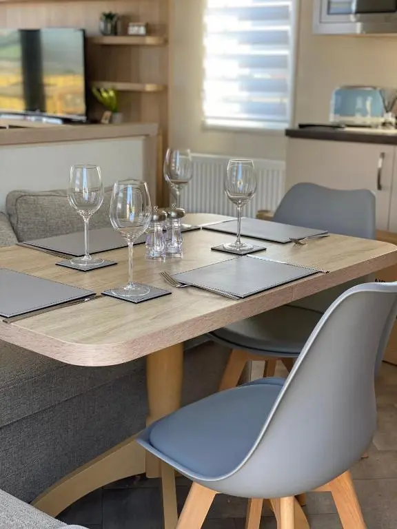 a wooden table with wine glasses on top of it at Beachfront Lodge, Lossiemouth Bay in Lossiemouth