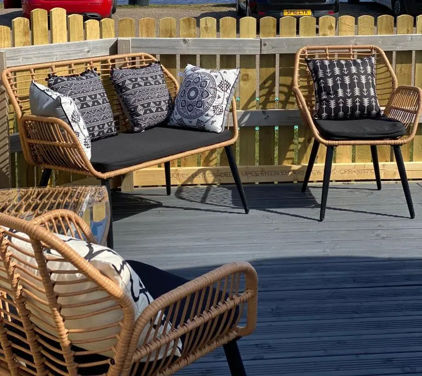 two wicker chairs with pillows on a patio at Beachfront Lodge, Lossiemouth Bay in Lossiemouth
