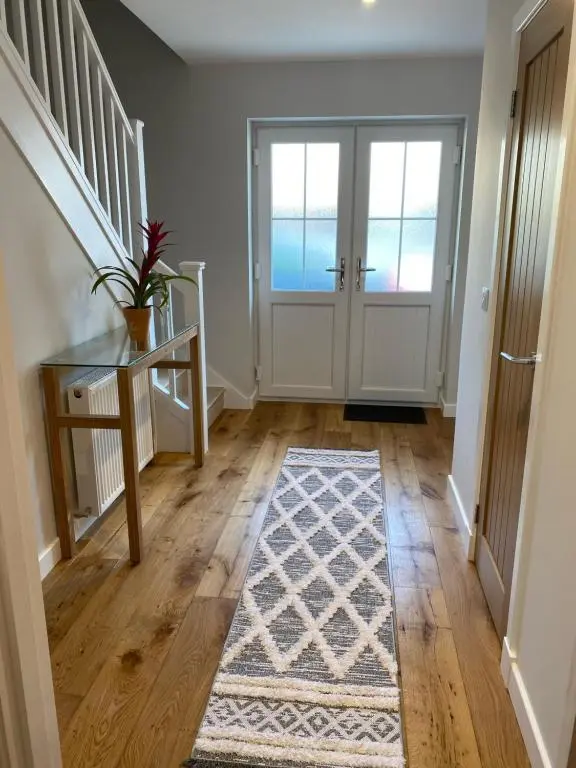a hallway with a staircase and a door with a rug at Loch Ness House Blairbeg in Drumnadrochit