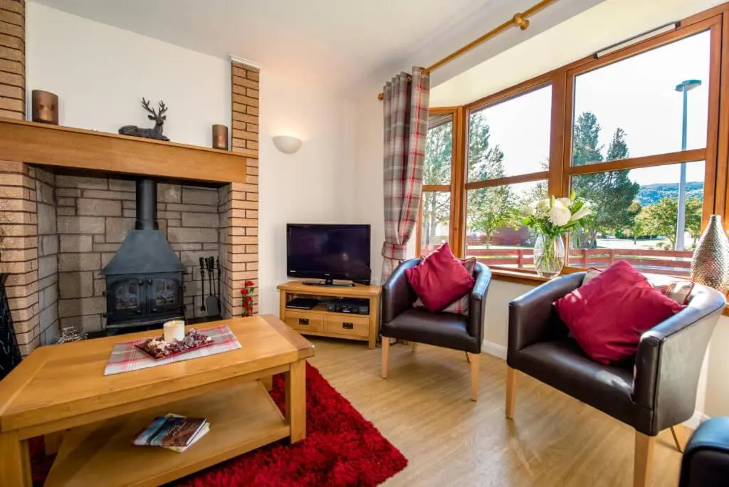a living room with two chairs and a fireplace at Silverglades Holiday Homes in Aviemore