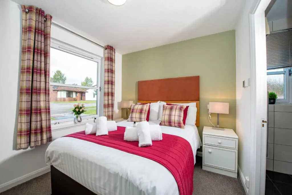 a bedroom with a large bed with a red blanket at Silverglades Holiday Homes in Aviemore