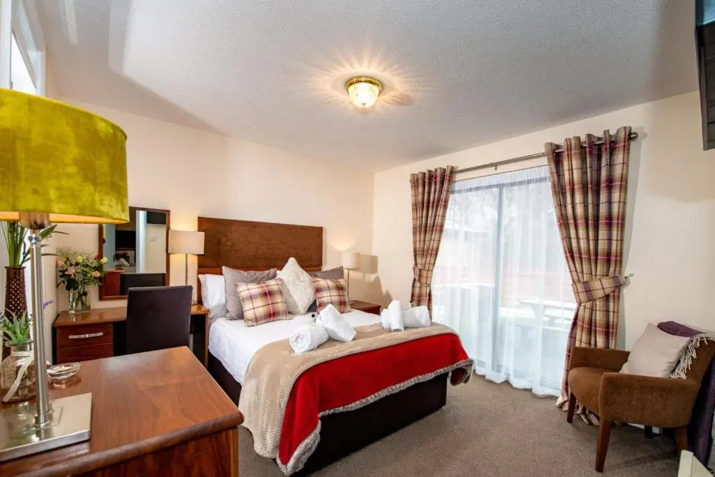 a bedroom with a bed and a desk and a window at Silverglades Holiday Homes in Aviemore