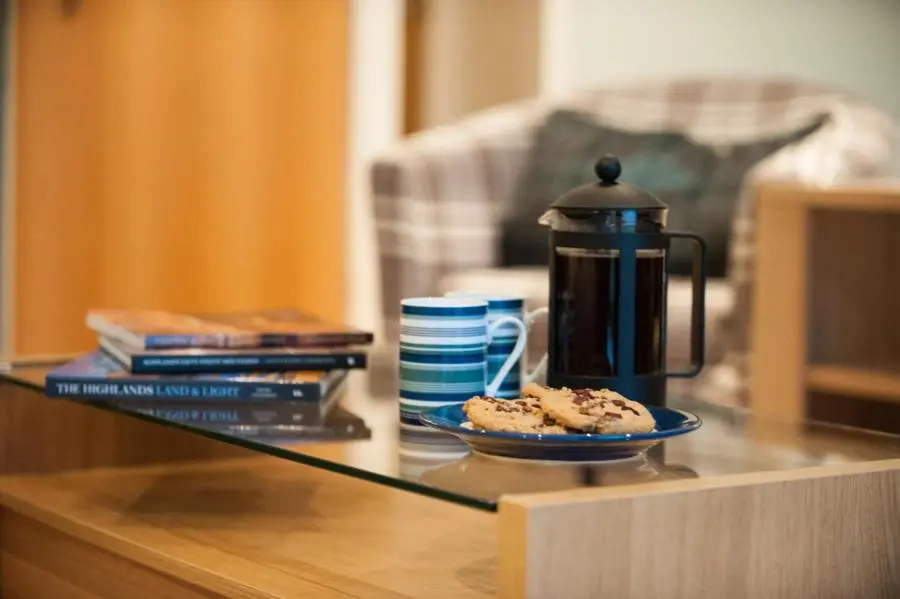 a table with a coffee pot and cookies on a plate at Glenwood Apartment at The Highland Club in Fort Augustus