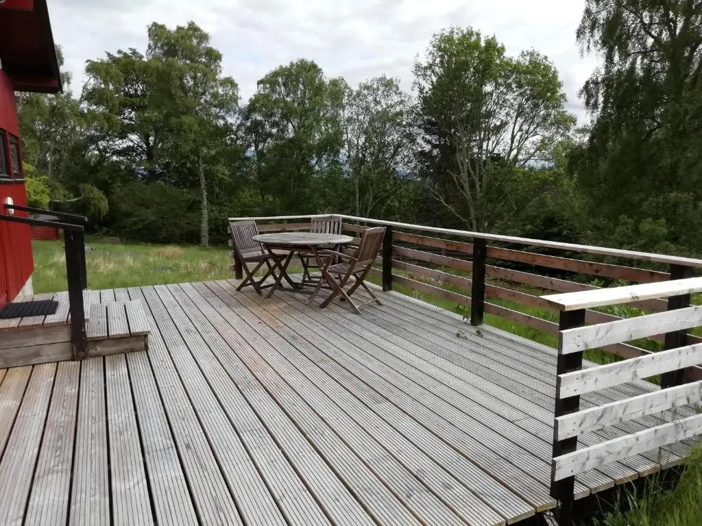a wooden deck with a table and chairs on it at Highland Lodge in Kilmorack