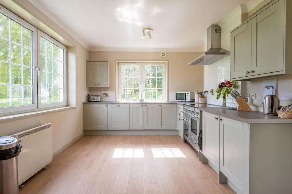 a kitchen with white cabinets and a large window at Braemoray in Evanton