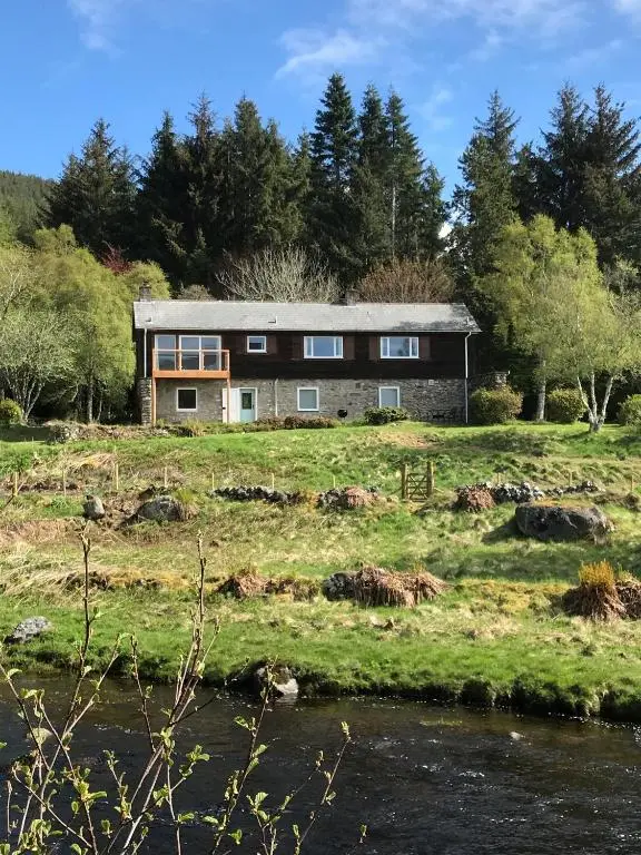 a stone house on a hill next to a river at Strone in Boath