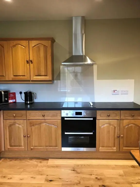 a kitchen with wooden cabinets and a stove top oven at Strone in Boath