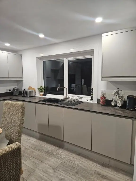 a kitchen with white cabinets and a sink and a window at No 14, 3 BED all with SMART TV's, Fully Fitted Kitchen, Ample PARKING, Ideal for TRADES, BUSINESS wanting comfort and a quality service REDUCTIONS FOR LONGER STAYS Langley Cottages and Apartments, in Wick