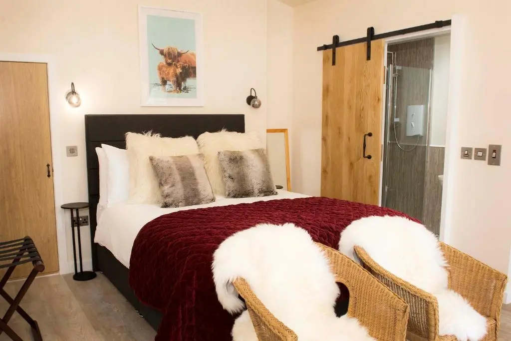 a bedroom with a large bed with a red blanket at Pear Tree Cottage in Cullen