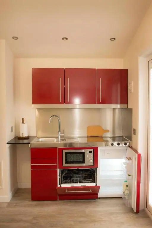 a kitchen with red cabinets and a sink at Pear Tree Cottage in Cullen