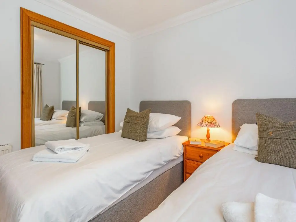 two twin beds in a bedroom with a mirror at Moray Firth View in Nairn