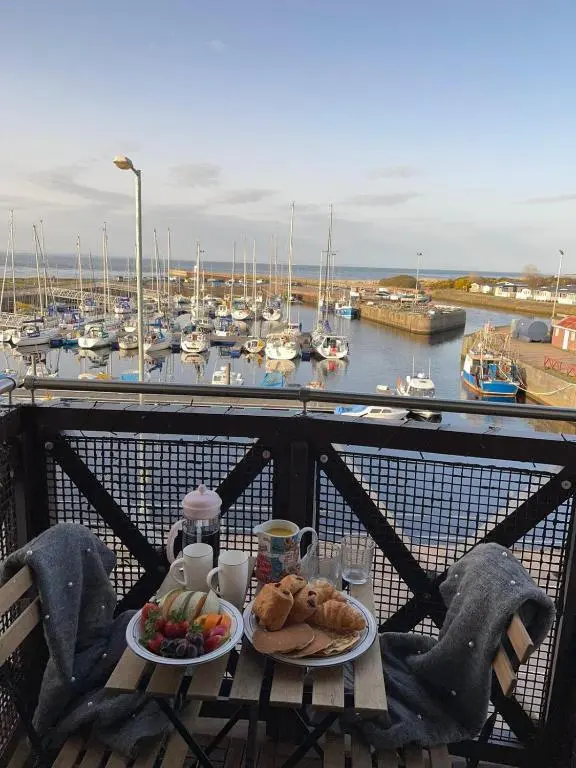 a table with food on a balcony with a marina at Harbour and River View, Beach 50m from doorstep & free parking in Nairn