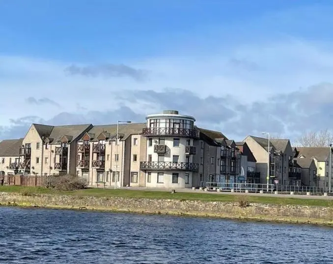 a large building next to a body of water at Harbour and River View, Beach 50m from doorstep & free parking in Nairn