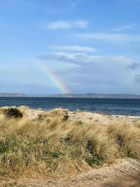 a rainbow in the sky over the ocean and a beach at Harbour and River View, Beach 50m from doorstep & free parking in Nairn
